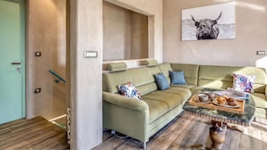 Een moderne woonkamer met een hoekbank, een salontafel met een schaal muffins en een wandkunst van een stier.