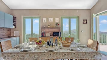 A dining area with a table set for four, kitchen cabinets, a window, and a balcony view.