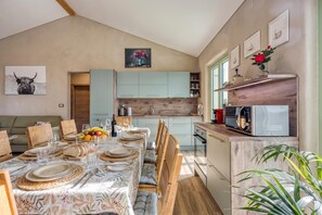 Un comedor con una mesa dispuesta para seis, una cocina con armarios azul claro y un microondas en la encimera.