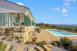 Una casa moderna con fachada de piedra, piscina y vistas al campo.