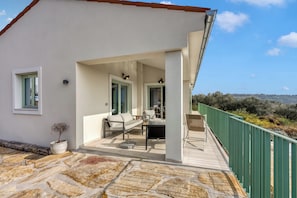 A modern house with a covered patio, a dining area, and a view of the countryside. - Villa Olivia with Sauna (Piran)