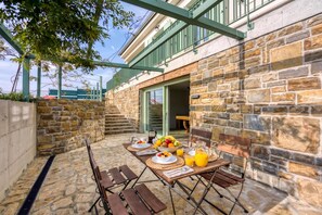 An outdoor dining area with stone walls, wooden tables, and chairs. - Villa Olivia with Sauna (Piran)