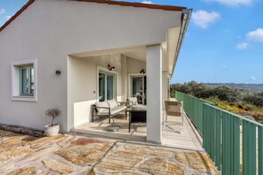 A modern house with a covered patio, a dining area, and a view of the countryside. - Villa Olivia with Sauna (Piran)