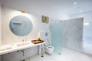 A modern bathroom with a round mirror, a sink, a toilet, and a shower area. - YAAN Estates (Khamnor)