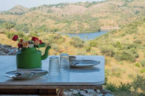 A table set outdoors with a green kettle, plates, glasses, and a bouquet of flowers. - YAAN Estates (Khamnor)