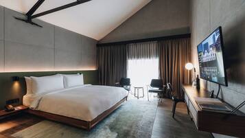 Une chambre d’hôtel moderne dotée d’un grand lit, d’un bureau, d’une télévision à écran plat et d’une fenêtre avec des rideaux.