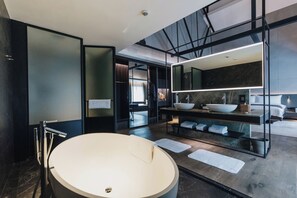 A modern bathroom with a large round bathtub, a double sink vanity, and a large mirror above the vanity.