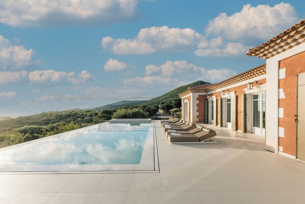 A swimming pool with lounge chairs and a view of hills. - Archontiko Stoufi, an Authentic SeaView Retreat (VMHW+8F Skinaria, Greece)