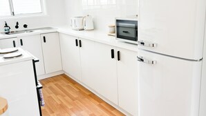 Una cocina moderna con armarios blancos, horno empotrado, microondas y refrigerador.