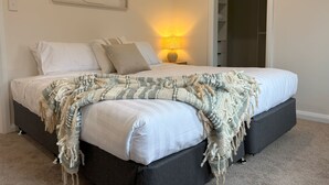 Un lit bien fait, avec une couette blanche et un plaid décoratif.