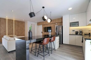 Enjoy dining and socializing at the kitchen's sleek island with bar stools, featuring a comfortable sofa and coffee station.