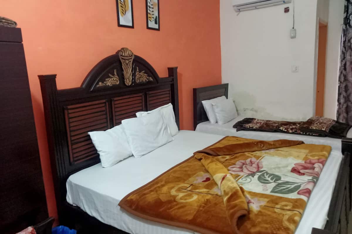 A bedroom with two beds, a wooden headboard, white bedding, and a floral blanket.