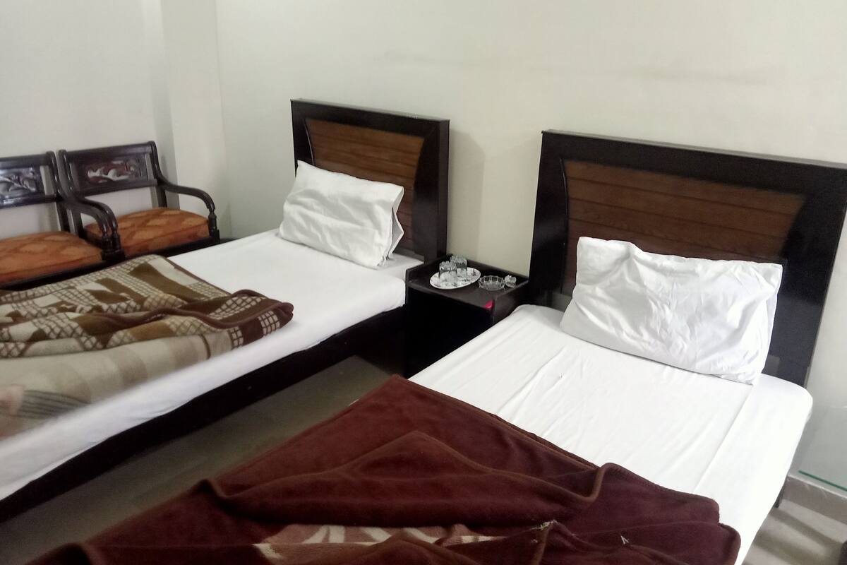 Two single beds with wooden headboards, white bedding, and a brown blanket on the floor.