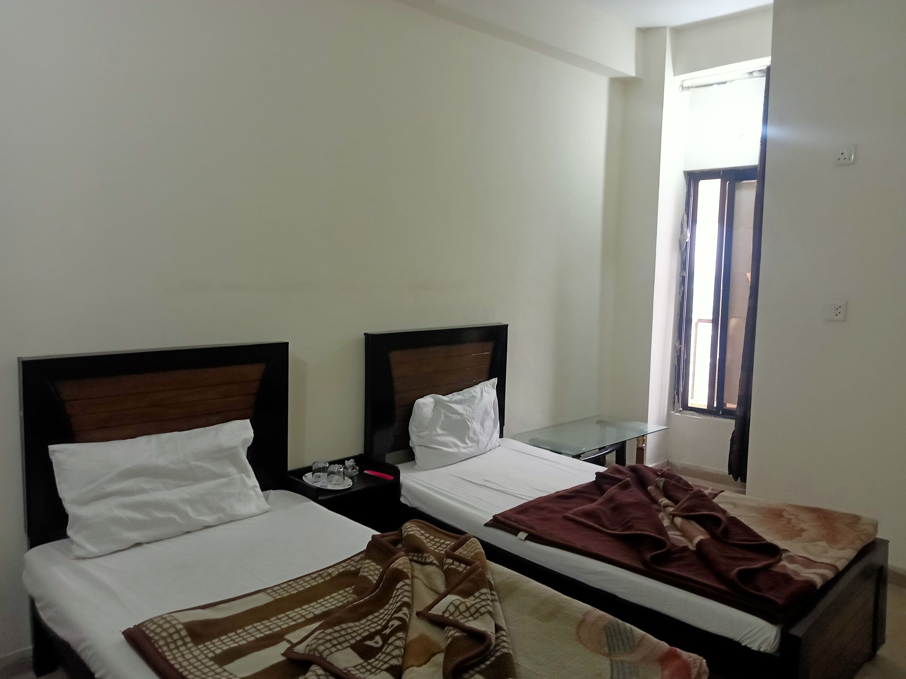 Ein Hotelzimmer mit zwei Einzelbetten, einem kleinen Tisch und einem Fenster.