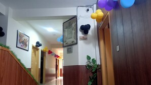 A hotel reception area with a reception desk, a wall-mounted sign, and a staircase with a green trim. - Nest Hotel (Rawalpindi)