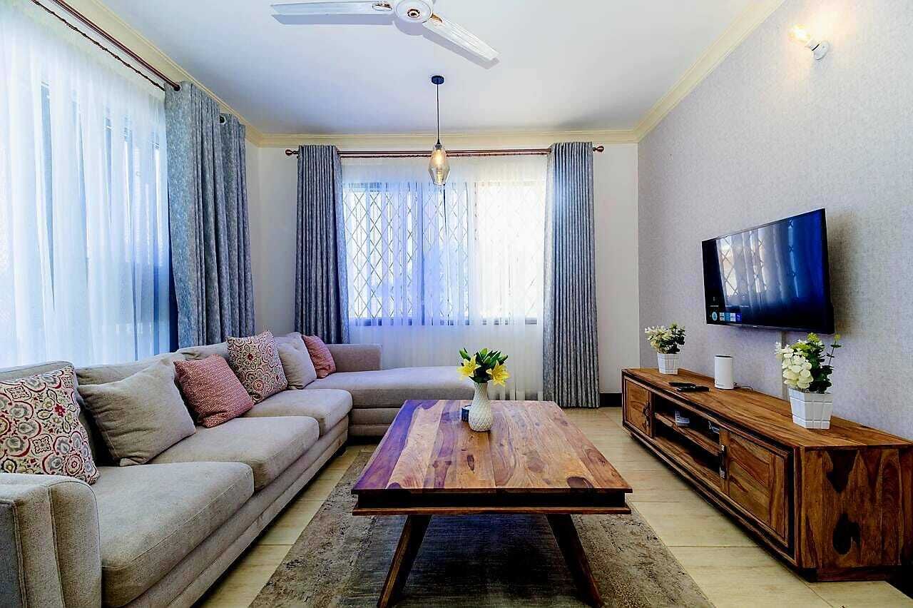 A living room with a sofa, coffee table, TV, and wooden cabinet.