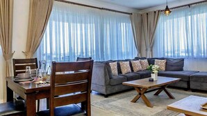 A living room with a sofa set, a dining table with chairs, and a coffee table. - Clalem Bay Condos by RevSerene (Mombasa)