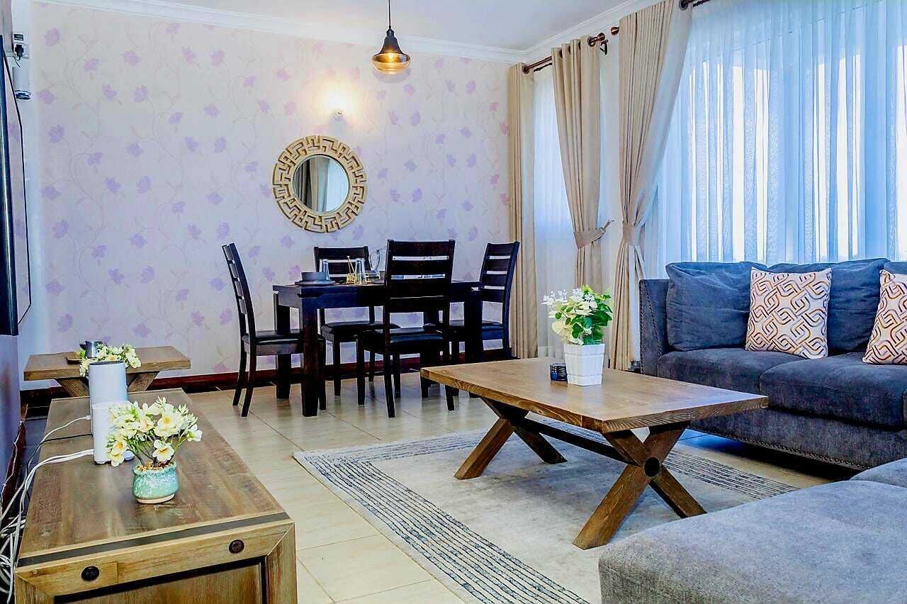 Ein Wohnzimmer mit einer Couch, einem Couchtisch, einem Esstisch mit Stühlen und einem dekorativen Spiegel an der Wand.