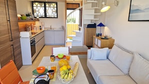 A modern kitchen with a dining area, a sofa, and a staircase leading to an upper level. - Sublime new apartment on the beach in ST FLORENT, 5' from the center (Saint-Florent)