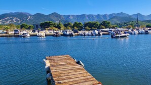 A marina with boats docked, a wooden pier in the foreground, and mountains in the background. - Sublime new apartment on the beach in ST FLORENT, 5' from the center (Saint-Florent)