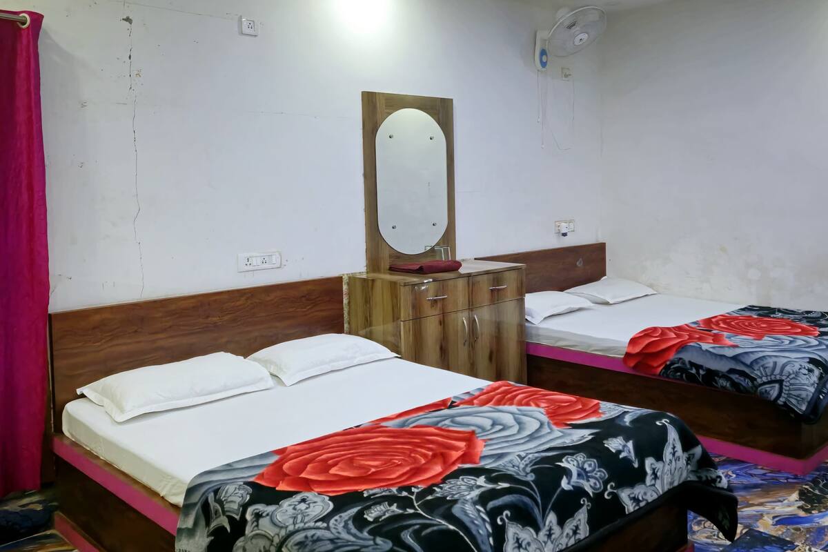 Een hotelkamer met twee bedden, een houten hoofdbord, een spiegel en een plafondventilator.