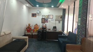 A reception area with a desk, chairs, and a wall adorned with religious statues and certificates.