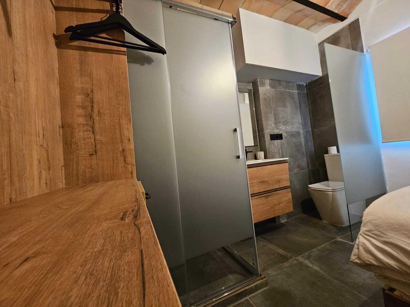 A modern bathroom with a wooden vanity, a glass shower enclosure, and a toilet.
