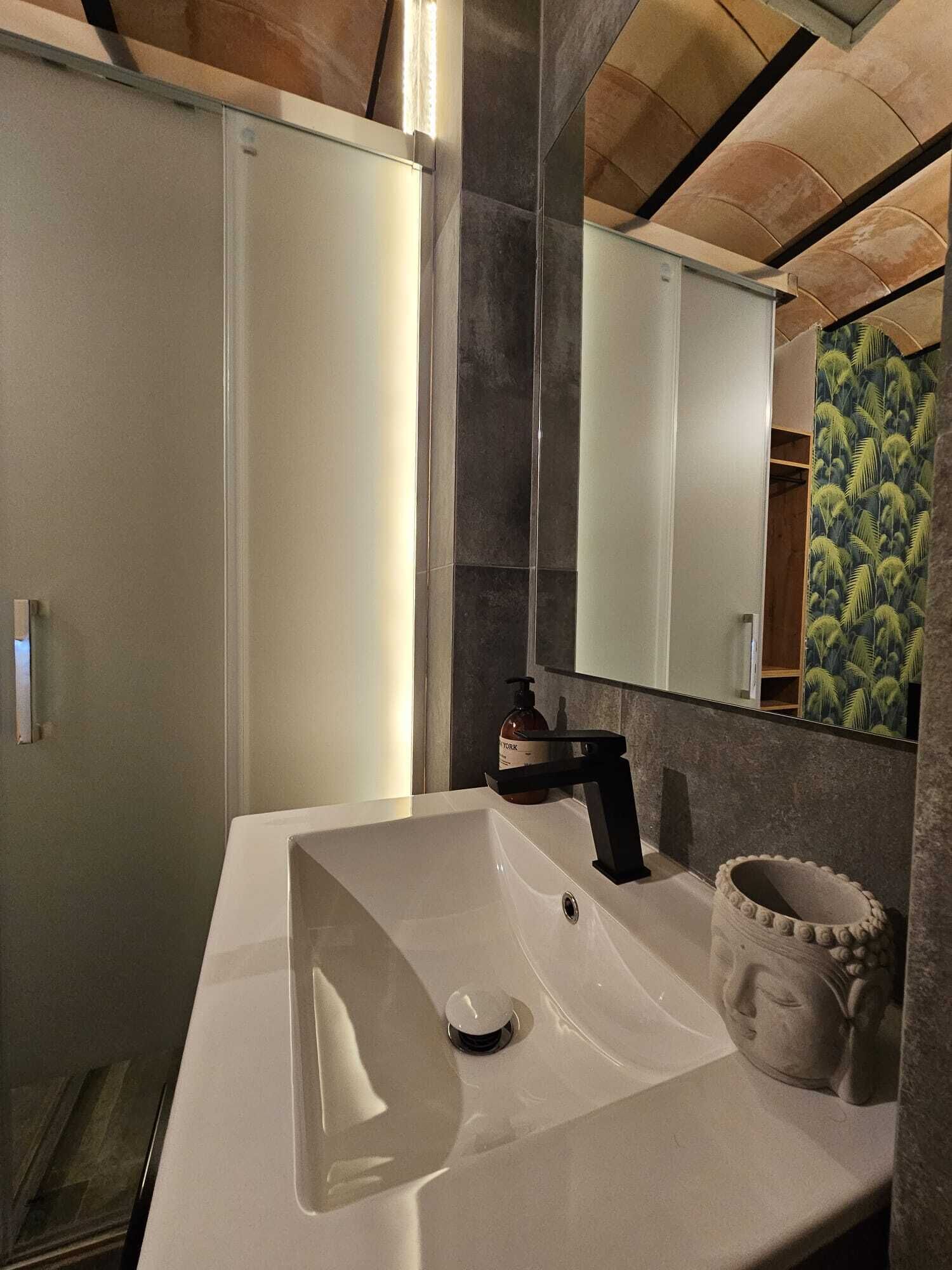 Une salle de bain moderne avec un lavabo blanc, un robinet noir et un grand miroir.