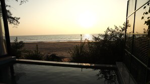 Vista desde un área junto a la piscina con vista a una playa al atardecer.