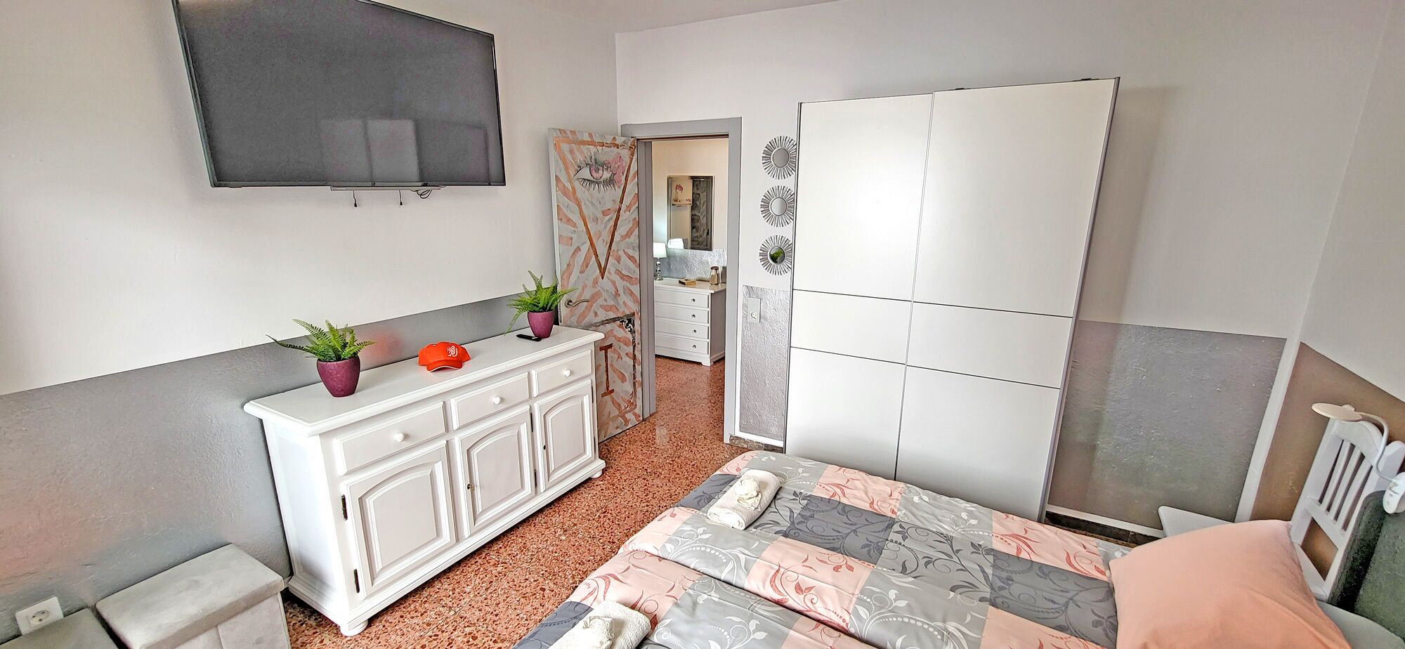 A bedroom with a bed, a dresser, a mirror, and a television.