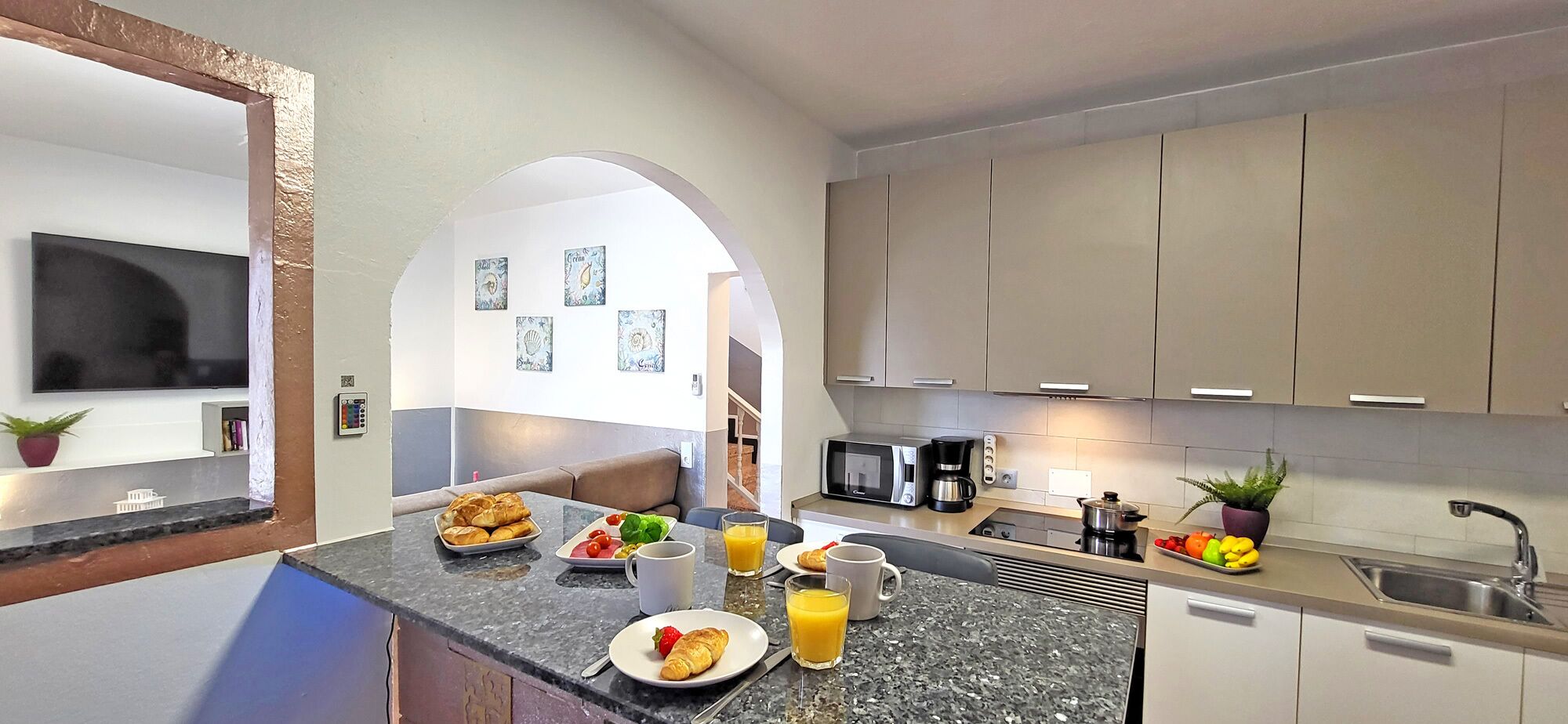 A modern kitchen with a dining area, featuring a granite countertop, stainless steel appliances, and a view into the dining room.