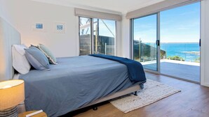 Ein Schlafzimmer mit Bett, Deckenventilator, großem Fenster und Meerblick.