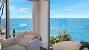 Ein Zimmer mit großen Fenstern und Meerblick, einer Couch und einem Sessel.