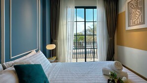 A hotel room with a large bed, a view of the outdoors through a window, and a painting on the wall. - Villa NovaWorld Phan Thiet 9 Trip STay (Tien Thanh)