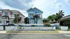 A two-story house with a white picket fence, a blue exterior, and a balcony. - Villa NovaWorld Phan Thiet 9 Trip STay (Tien Thanh)
