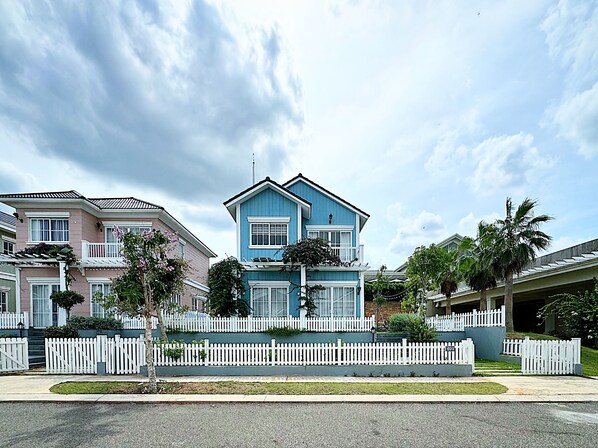 Een tweelaags huis met een witte picket fence, een blauwe gevel en een balkon.