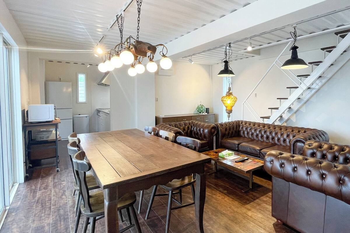 Eine moderne Küche mit Holztisch, Ledersofa und hängenden Pendelleuchten.