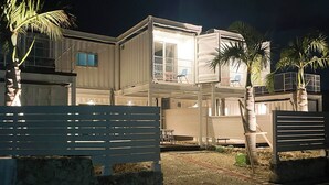 A multi-level house with balconies, a gated entrance, and palm trees. - Vamos Villa Tokunoshima (Tokunoshima)