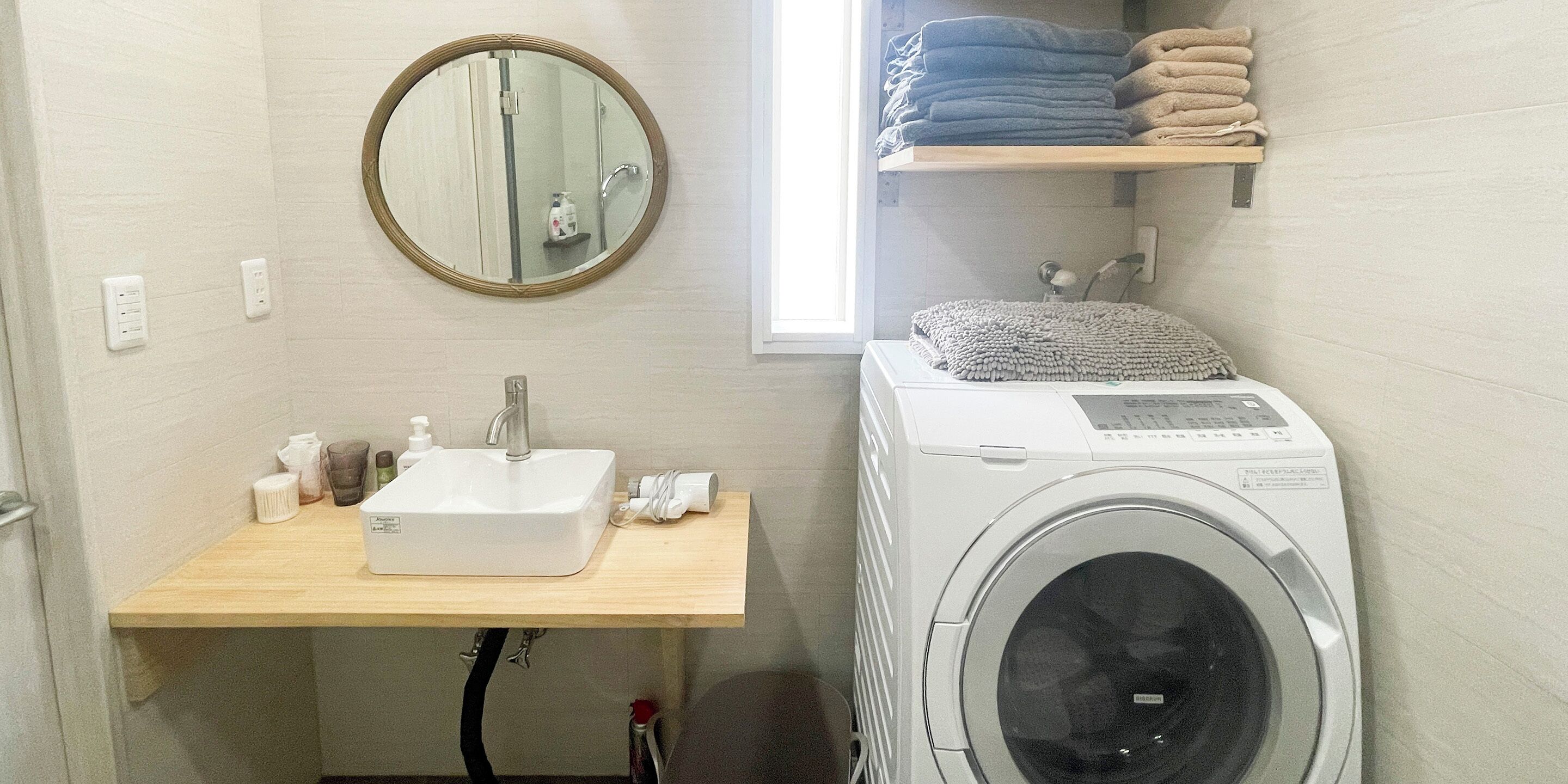 A compact bathroom with a sink, mirror, and stacked towels.