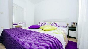 A bedroom with a bed, a nightstand, a mirror, and a door. - Apartments Perinic (Vrsi)