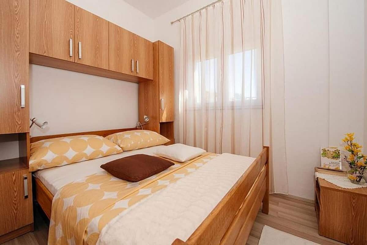 A bedroom with a wooden bed, a nightstand, and a window with curtains.