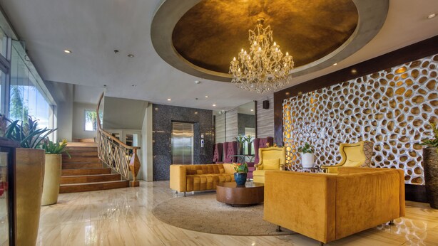 Een moderne lobby met een kroonluchter, een receptiebalie en een trap.