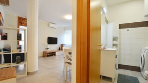 A modern living room with a flat-screen TV, a bookshelf, and a dining area. - Stylish and Modern Rovinj Apartment (Rovinj)