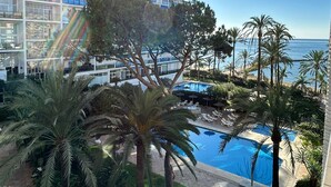 A hotel with a pool, palm trees, and a view of the ocean.