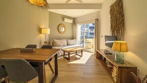 A modern living room with a wooden dining table, a sofa, and a TV.