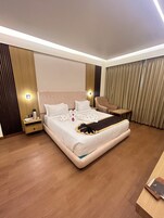 Una habitación de hotel moderna con una cama grande, mesitas de noche, una silla y un escritorio.