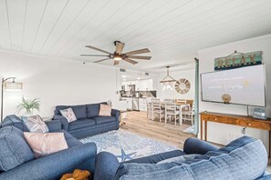 Un salon moderne avec un ventilateur de plafond, un téléviseur et un panneau indiquant « RELAX ».