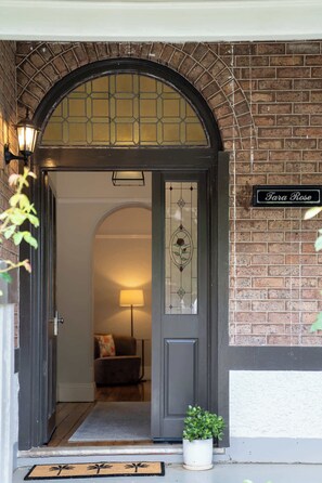 A brick house entrance with a dark archway, a glass door with a rose design, and a 'Tara Rose' sign. - Incredible Location! 2 Bed CBD Dream (Orange)