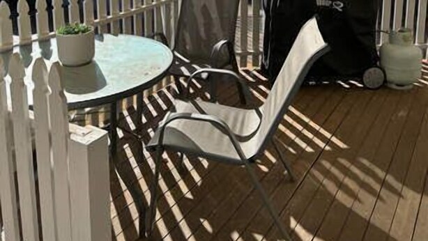 A covered patio with a round table and chairs, a white picket fence, and a barbecue grill. - Incredible Location! 2 Bed CBD Dream (Orange)