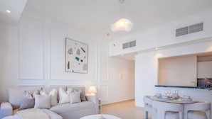A modern living room with a sofa, a dining table set for four, and a kitchen area visible through an open doorway. - LUX  The Silverene Marina View Suite 4 (Dubai)
